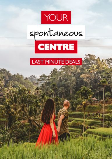 Your Spontaneous Centre - Last Minute Deals - Woman in a stunning red dress and her partner in boring clothes, in a palm tree filled forest