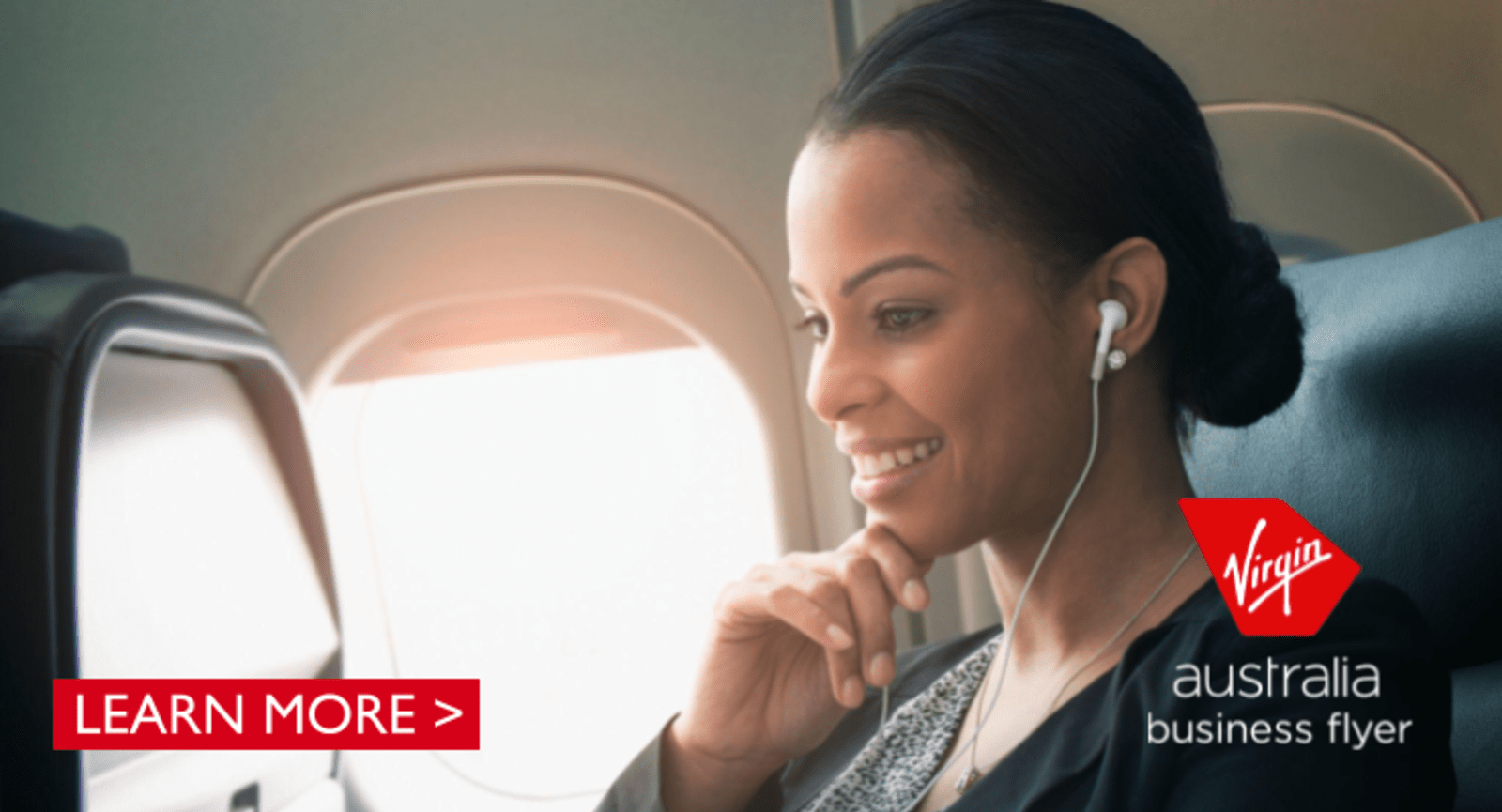 Woman with headphones watching something on a plane. Virgin Australia business flyer